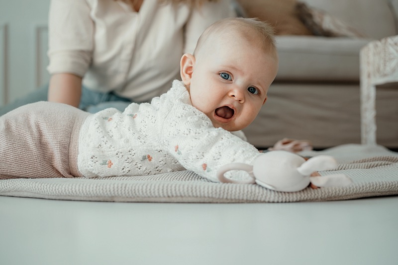 Baby ligt vrolijk op een kleedje