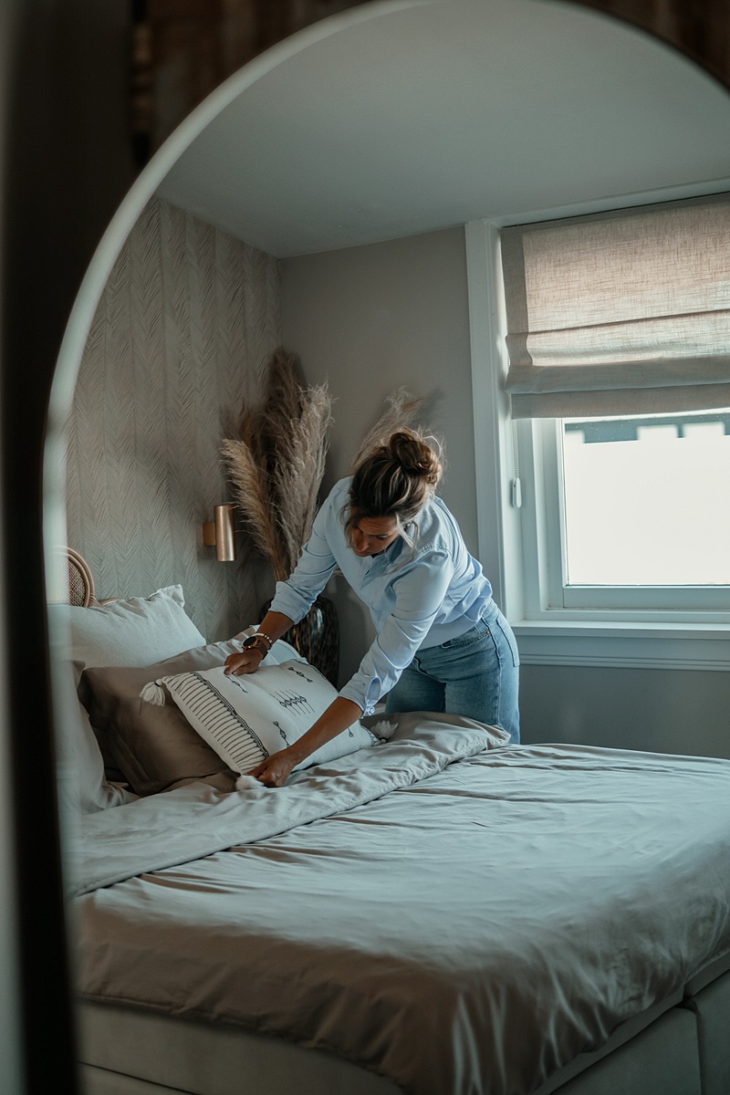 Bed wordt opgemaakt in een lichte slaapkamer
