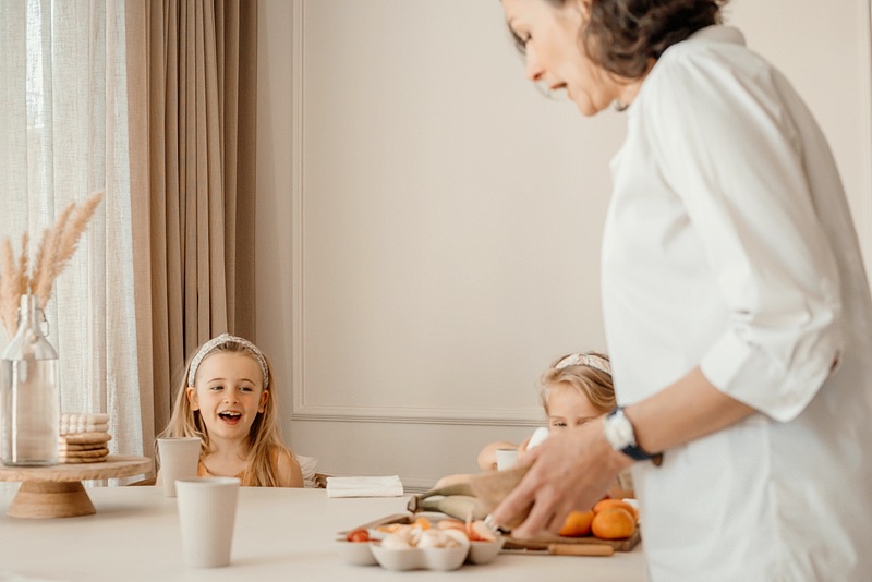 Family assistant en twee lachende meisjes aan tafel