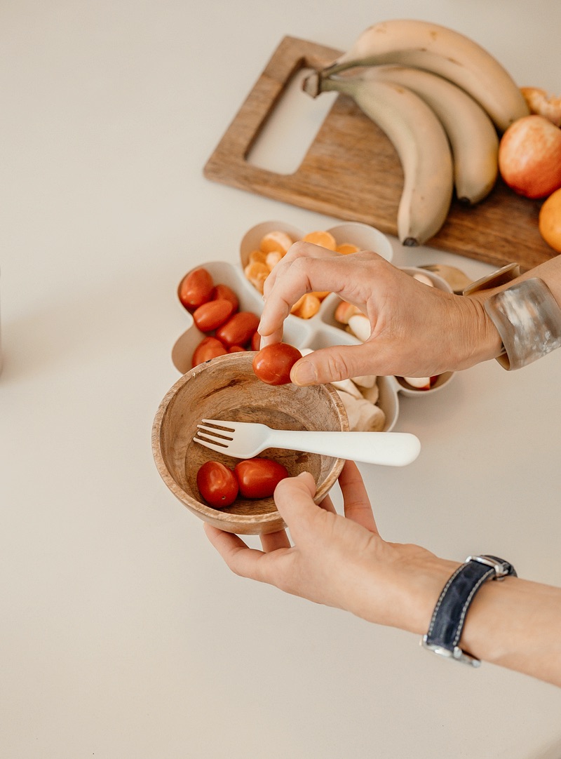 Handen maken een schaaltje fruit klaar