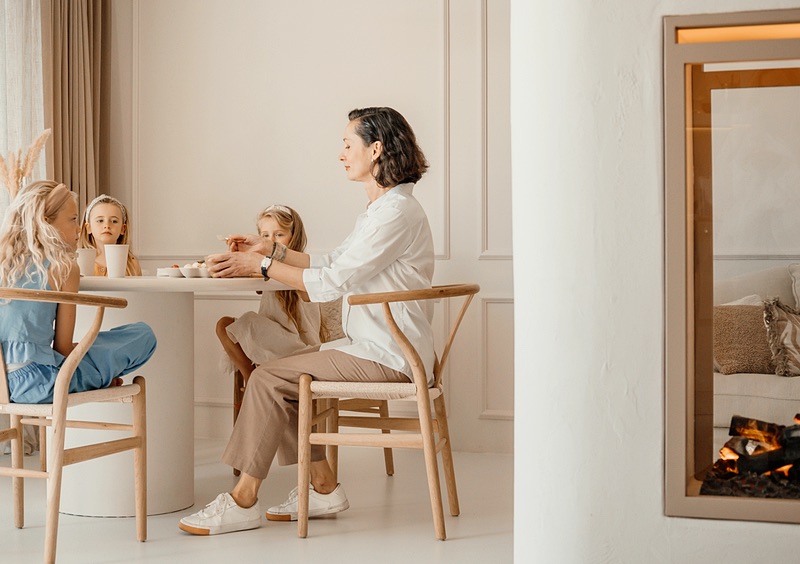 Family assistant sitting with two children at the dining table