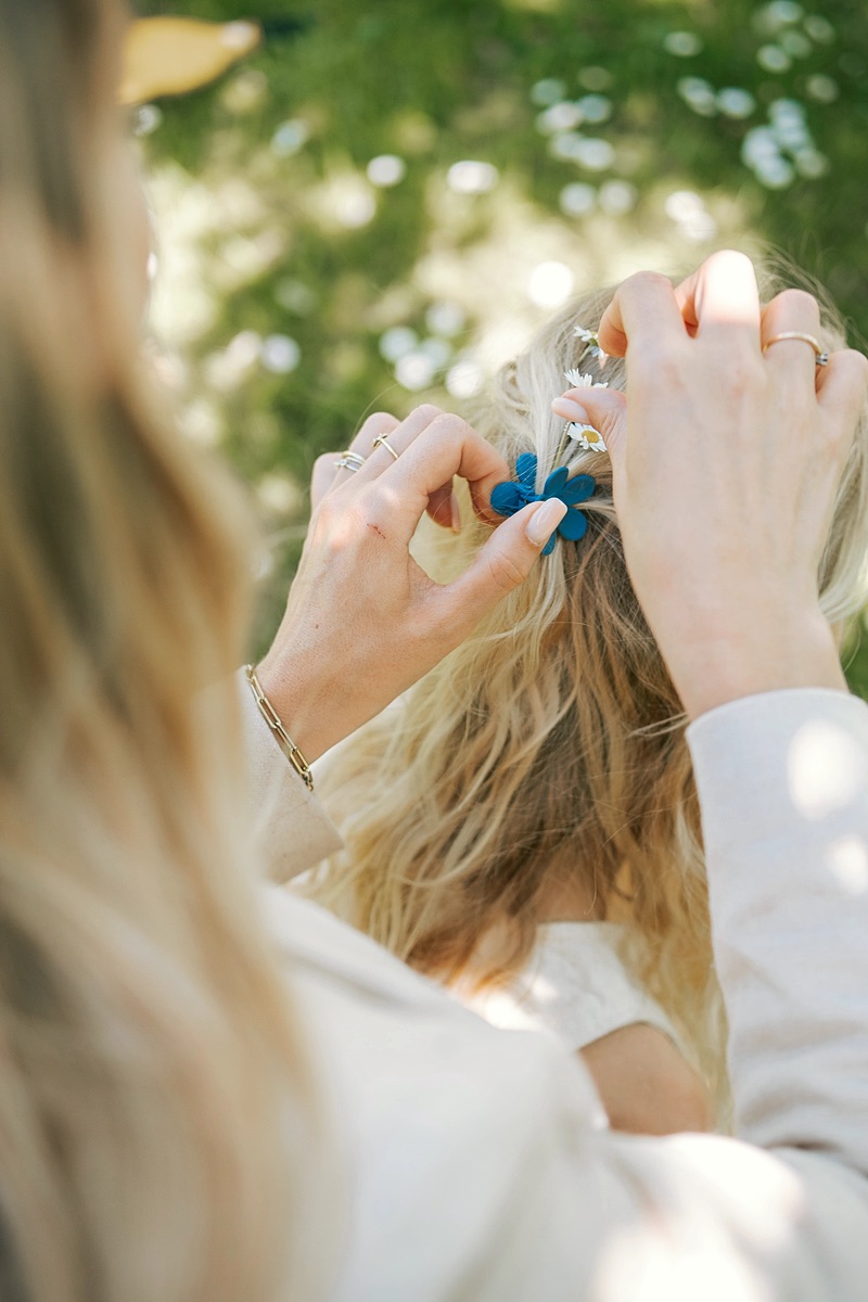 Handen doen een haarspeld in het haar van een meisje