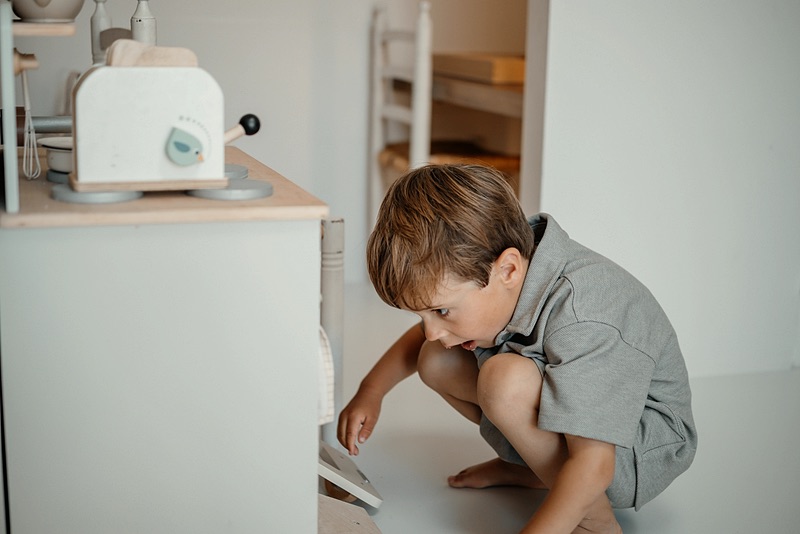 Jongen speelt met het speelgoedfornuis
