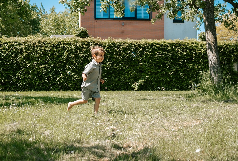 Boy running outside along the hedge
