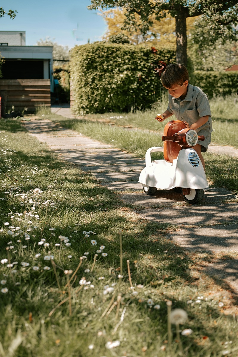 Jongen rijdt op een loopauto in de tuin