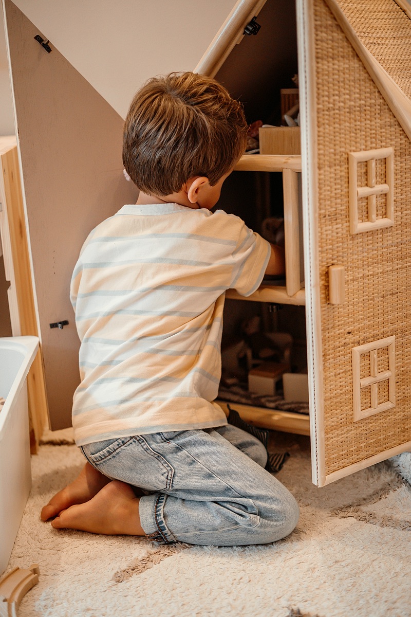 Jongen speelt met een houten poppenhuis