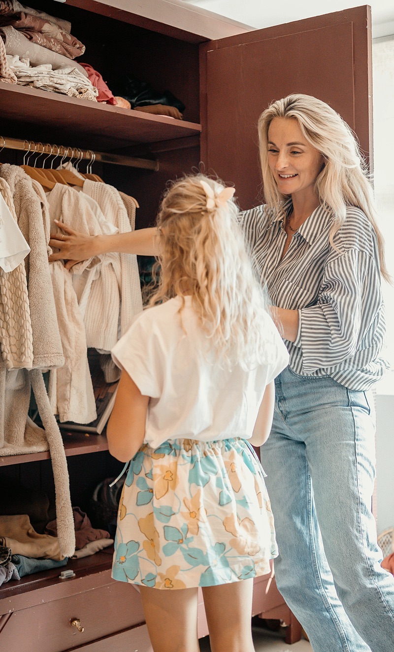 Nanny choosing clothes with a girl at the wardrobe