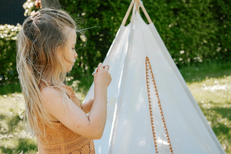 Meisje speelt bij een tipi in de tuin