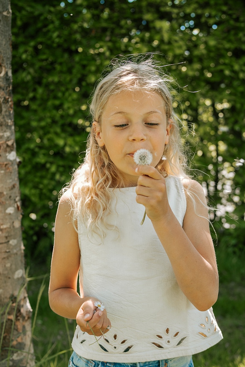 Meisje blaast een paardenbloem uit