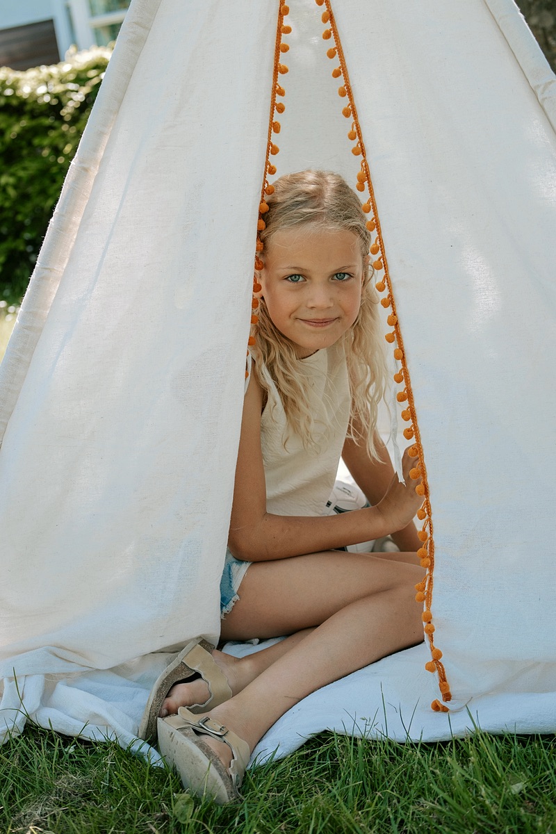 Meisje speelt in een tipi in de tuin