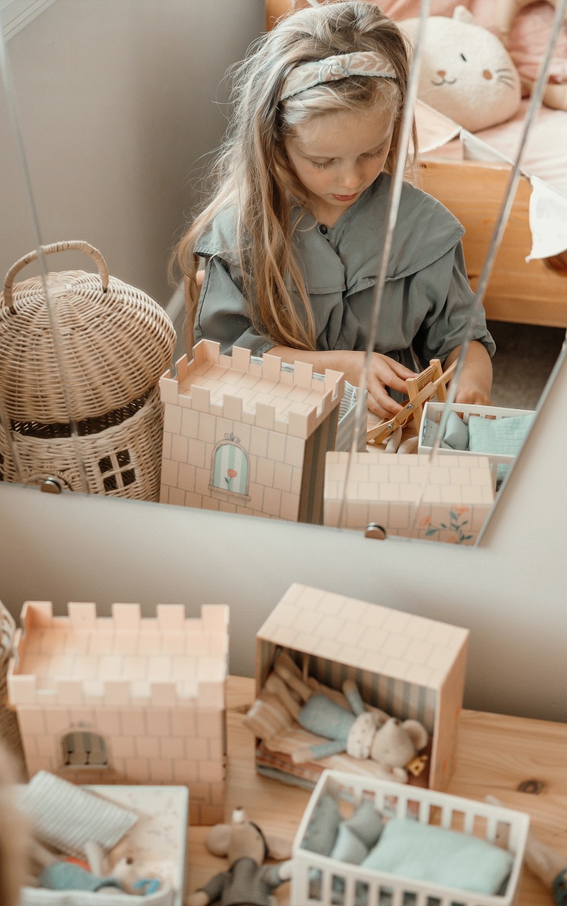 Meisje speelt met een houten poppenhuis