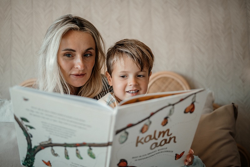 Nanny leest samen met een jongen een boek