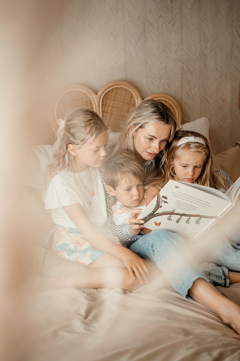 Nanny leest op bed voor aan drie kinderen