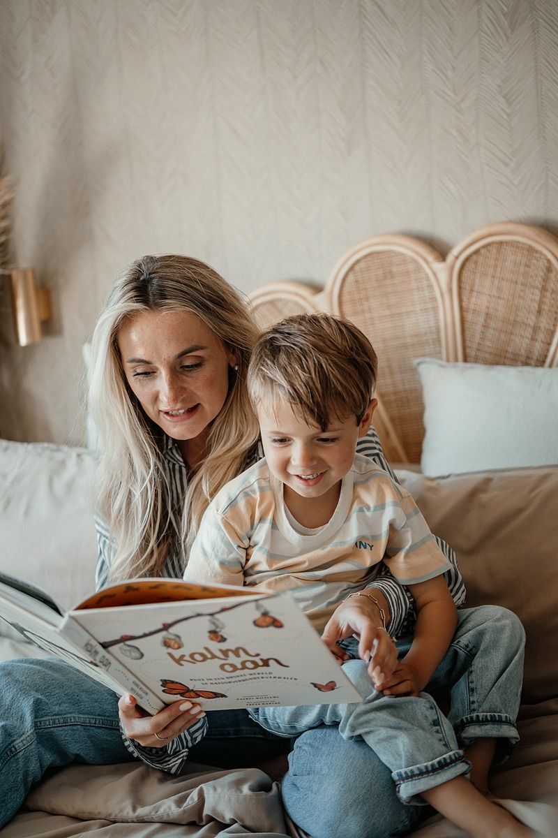 Nanny leest een prentenboek voor aan een jongen op bed