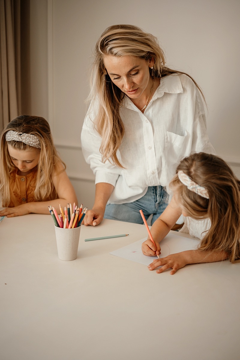 Nanny tekent samen met twee meisjes aan tafel